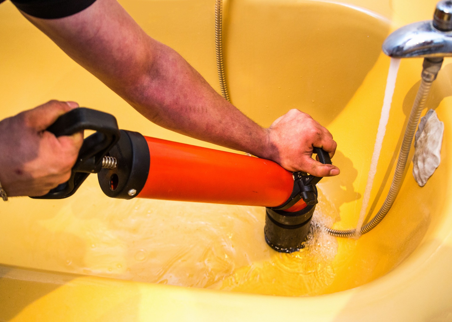 Plumber cleaning drain in bathroom