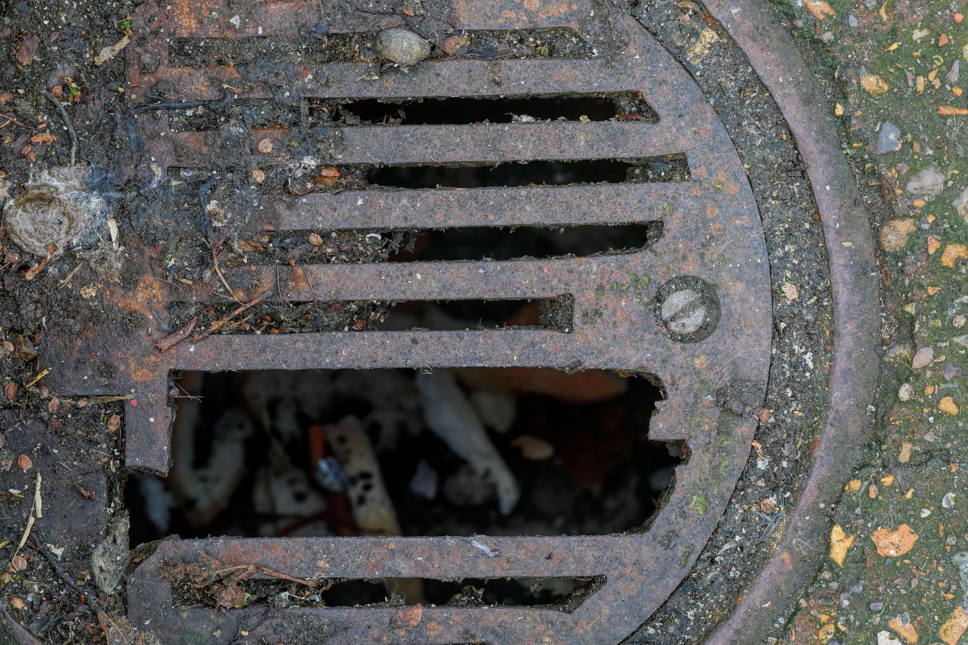 Broken metal drain cover blocked with mud